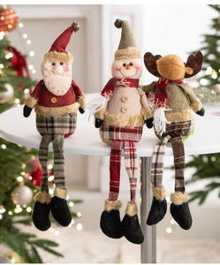 Three plush Christmas dolls featuring Santa, Snowman and Reindeer on a festive table