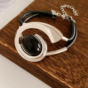Detail of silver oval black gemstone bracelet with adjustable black braided rope