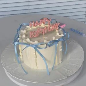 Detail of white cream cake with light blue ribbon bows and pink happy birthday topper
