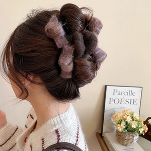 Detailed view of a purple and brown plush bow hair claw clip worn on thick hair