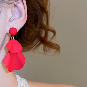 Detailed close-up of matte red petal tassel earrings with textured floral details on model