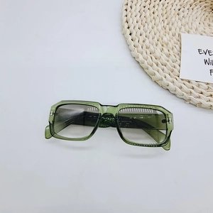 Detail der olivgrünen rechteckigen Sonnenbrille mit Silbernieten auf Strohmatte