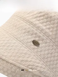 Detailed close-up of beige sun hat featuring honeycomb texture and metal logo