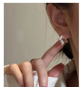 Close-up of S925 silver knotted earrings and matching textured ring on model