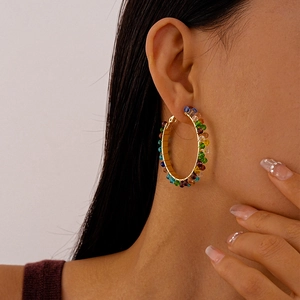 Close-up of a model wearing colorful beaded hoop earrings with silver pins and wire wrap