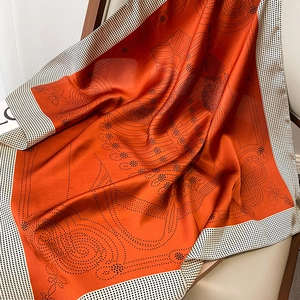 Detailed texture of orange silk scarf with black polka dots on light leather seat
