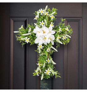Detail of Easter door wreath with white lilies and green foliage on dark wood background