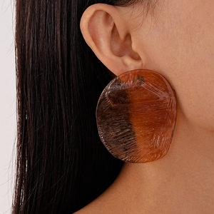 Close-up of a large amber resin hoop earring with vintage textured finish on a model