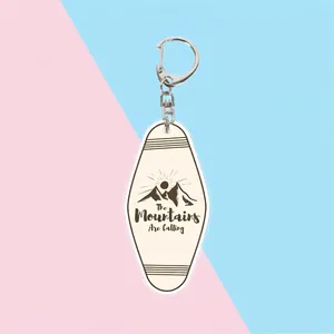 Acrylic mountain keychain with The Mountains Are Calling slogan and vintage oval shape