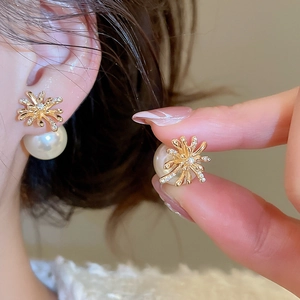 Close-up of gold-plated firework earrings with white pearls and sparkling cubic zirconia
