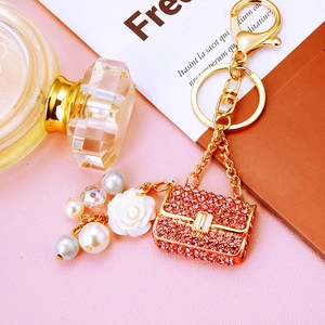 Detailed shot of pink rhinestone handbag keychain with camellia flower and pearls
