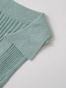 Detaillierte Makroansicht der minzgrünen Stricktextur und feinen Kantennahtdetails