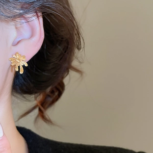 Close-up of gold-plated flower stud earring worn by a model with a minimalist style