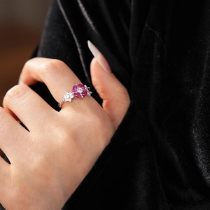 Detail of rose red zircon flower ring with silver band on a black velvet background