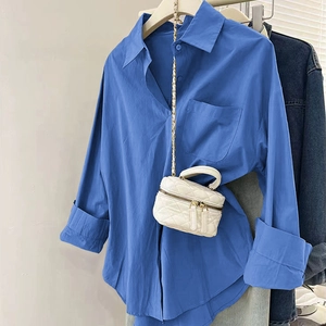 Détail d'une chemise bleue en coton à manches longues avec petit sac matelassé blanc