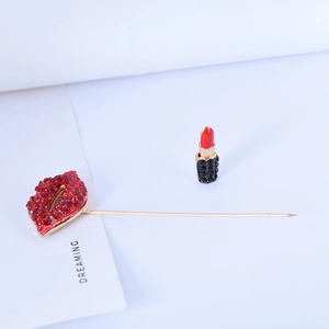 Detail of fashion red lip brooch with rhinestones and gold pin on a white card
