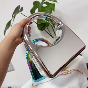 Detail of silver mirror acrylic evening clutch featuring a metallic handle and gold chain