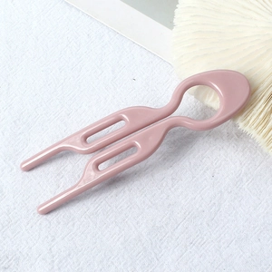 Detail view of the pink U-shaped hair pin for bun styling with glossy resin finish