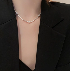 Detailaufnahme eines silbernen Perlen-Chokers mit Metallelementen auf schwarzem Blazer