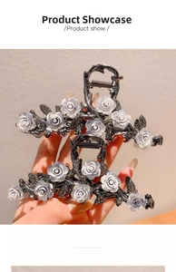 Detail of a large dark metal shark hair claw clip with white rose floral design