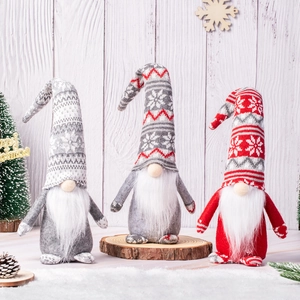Three Christmas gnomes with knitted hats and white beards on a winter wooden background
