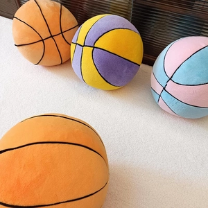 Collection of soft plush basketball pillows in vibrant colors on a white fluffy carpet