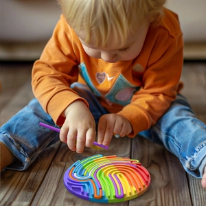 Toddler playing with rainbow silicone sensory activity board using a purple stylus