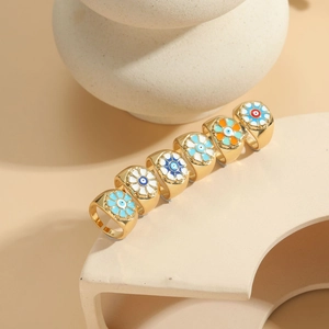 Detail view of 14K gold plated rings with colorful enamel evil eye and flower patterns