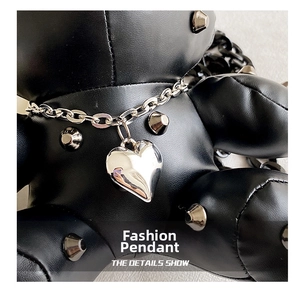 Detail of a punk style silver metal heart charm on black PU leather with metallic studs