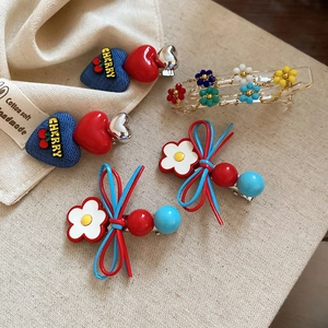 Flat lay of floral leather bow hair clips and beaded flower hair claws on linen fabric