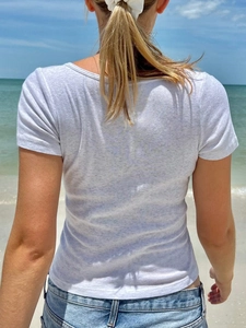 Rear view of white ribbed knit short sleeve T-shirt worn by model on a sunny beach