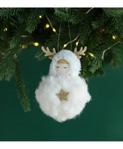 White plush angel Christmas ornament with golden antlers hanging on a festive tree branch