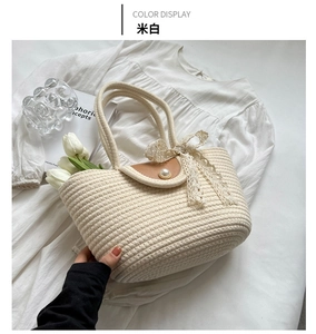 Detail of cream woven tote bag with lace bow, pearl button, and brown leather flap