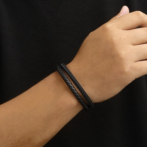 Detail showing layers of braided black leather bracelet with magnetic clasp on wrist