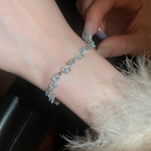 Close-up of aquamarine zircon bracelet with silver metal bow and blue gemstones