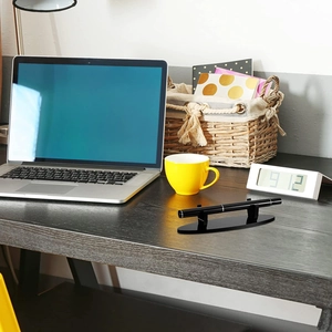 Detail view of a black acrylic desk pen stand on a dark wood surface for office storage