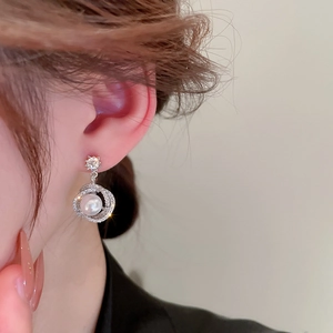 Close-up of elegant flower pearl earrings with sparkling zircons and silver circles