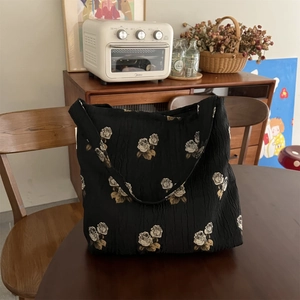Detail of vintage black jacquard tote bag with white rose texture on a wooden desk