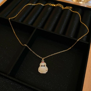 Macro detail of gold-plated gourd pendant with white cat-eye stone and tiny gems