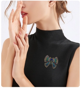 Detail of vintage bronze butterfly brooch with blue and green crystals on sweater