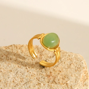 Vintage 18K gold plated stainless steel ring with oval green gemstone on a natural rock