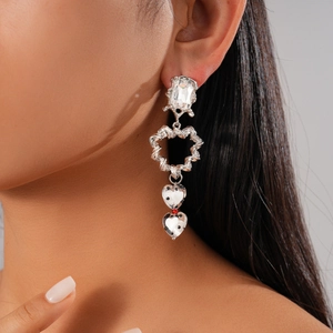 Détail de boucles d'oreilles cœur torsadées en argent avec cristaux portées par le mannequin
