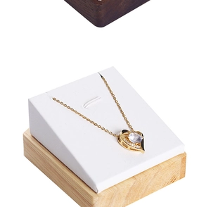 Detail view of heart pendant necklace with gold chain on a wooden display stand