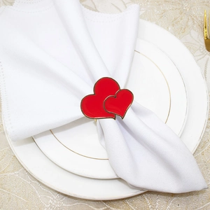 Detail of red double heart napkin ring with gold trim on white napkin and plate