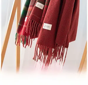 Detail of red and green plaid fringe scarf with thick knit texture and brand label
