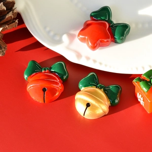 Detailed view of festive Christmas bell and gift box resin charms on red background