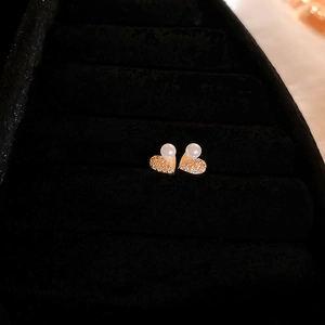 Close-up of gold heart stud earrings with pearls and pavé zircons in a black velvet box