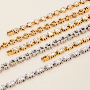 Detail view of 18K gold and silver stainless steel bracelets with square zircon charms