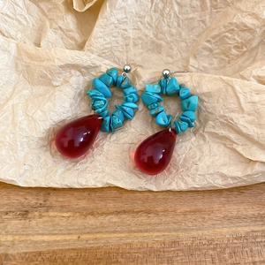 Detail of ethnic style earrings with turquoise beads and red water drop resin pendants