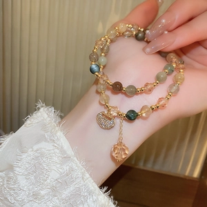 Detail of multi-layer beaded bracelet with golden lock pendant and crystal on wrist